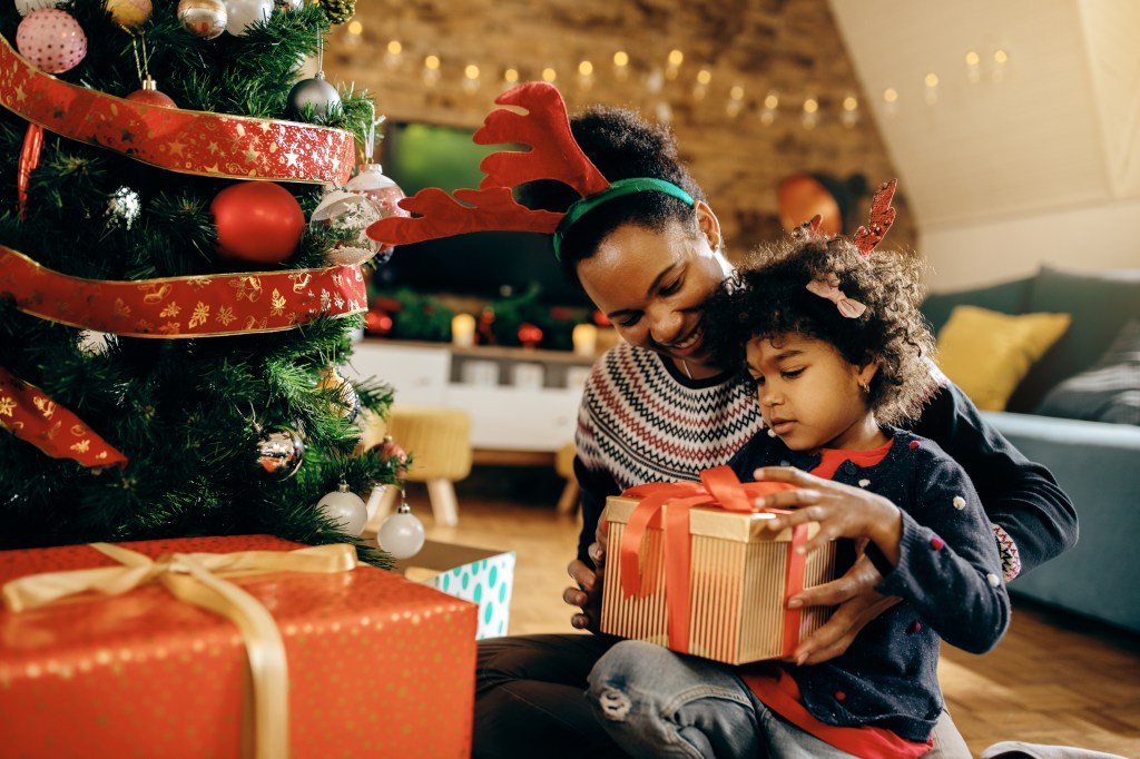 Happy African American mother and daughter opening Christmas presents 